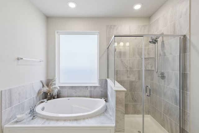 bathroom with a shower stall, a bath, and recessed lighting