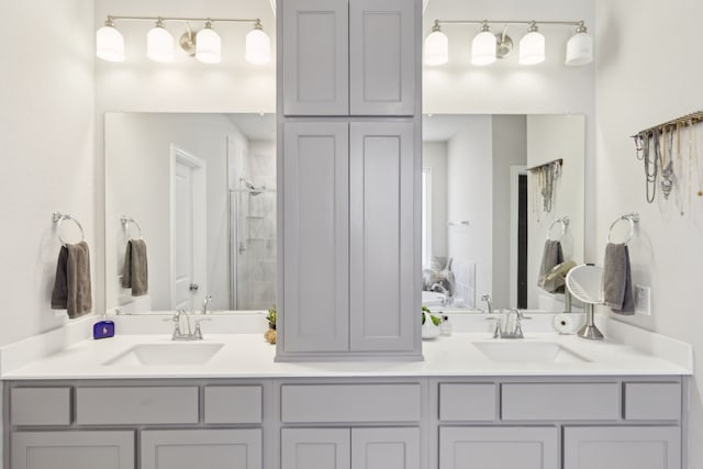 full bath featuring a tile shower, double vanity, and a sink