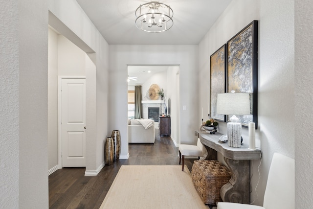 hall featuring baseboards, an inviting chandelier, and wood finished floors