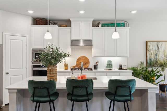 kitchen with white cabinets, decorative backsplash, appliances with stainless steel finishes, extractor fan, and pendant lighting