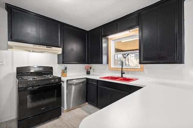 kitchen with under cabinet range hood, black range with gas stovetop, dark cabinetry, and dishwasher