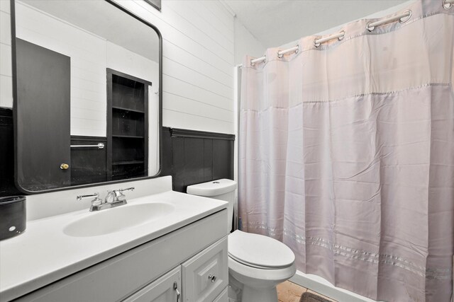 full bathroom with curtained shower, vanity, toilet, and wooden walls