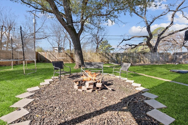 view of yard with an outdoor fire pit, a trampoline, and a fenced backyard