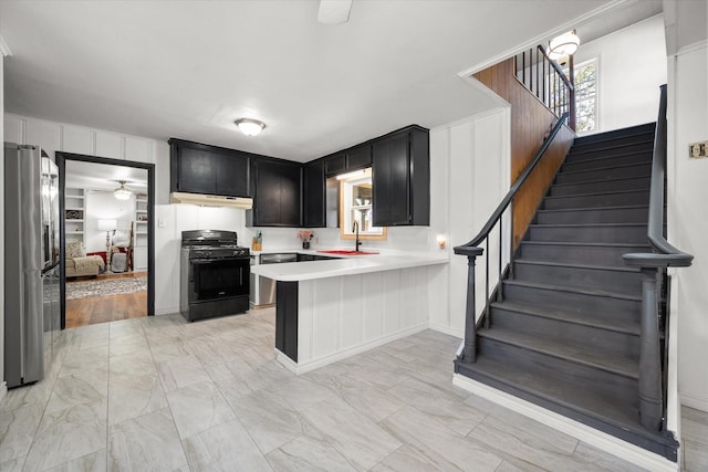 kitchen with stainless steel appliances, light countertops, a sink, dark cabinets, and a peninsula