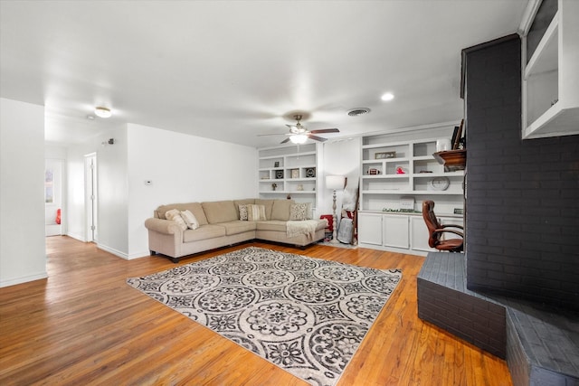 living room with a ceiling fan, light wood-type flooring, visible vents, and baseboards