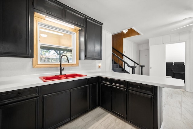 kitchen featuring dark cabinetry, a sink, and a peninsula