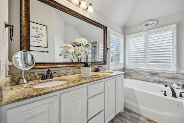 bathroom with lofted ceiling, double vanity, a sink, and a bath