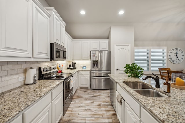 kitchen with white cabinets, decorative backsplash, stainless steel appliances, a sink, and recessed lighting