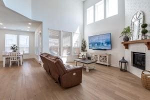 living room featuring a fireplace, wood finished floors, and a towering ceiling