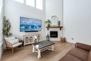 living room with baseboards, a large fireplace, a high ceiling, and wood finished floors