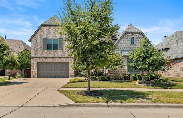 view of front of house with an attached garage, brick siding, concrete driveway, and a front yard