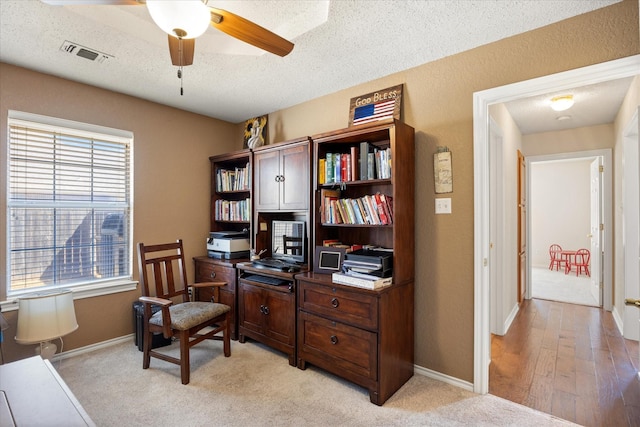 office area with a textured ceiling, ceiling fan, visible vents, and baseboards