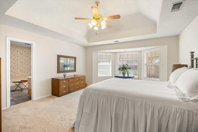 carpeted bedroom featuring a raised ceiling, visible vents, a textured ceiling, and baseboards