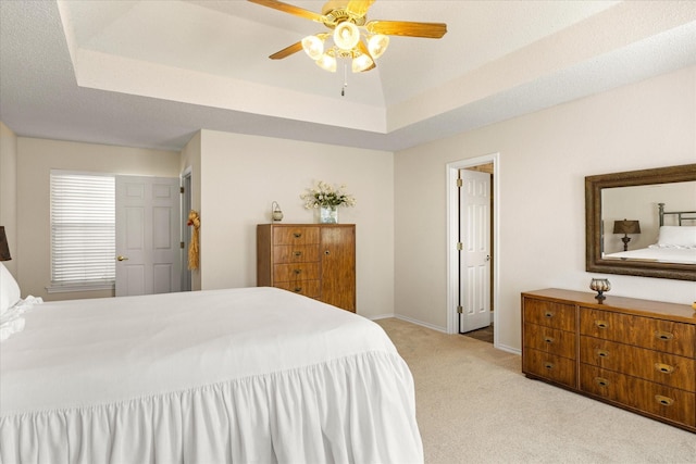 bedroom with baseboards, ceiling fan, a raised ceiling, and light colored carpet