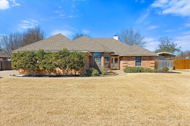 view of front of home featuring a chimney, roof with shingles, fence, a front yard, and brick siding