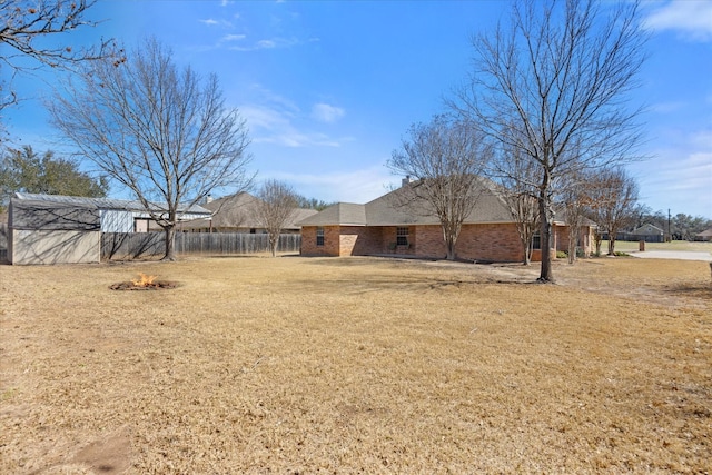 view of yard with an outdoor fire pit, fence, and an outdoor structure