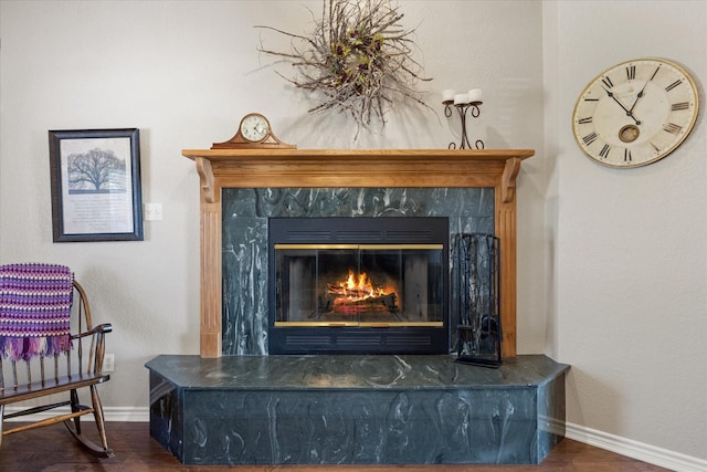 details with baseboards, wood finished floors, and a tile fireplace