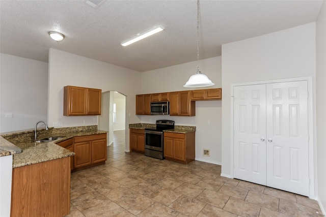 kitchen featuring arched walkways, stainless steel appliances, brown cabinetry, and a sink