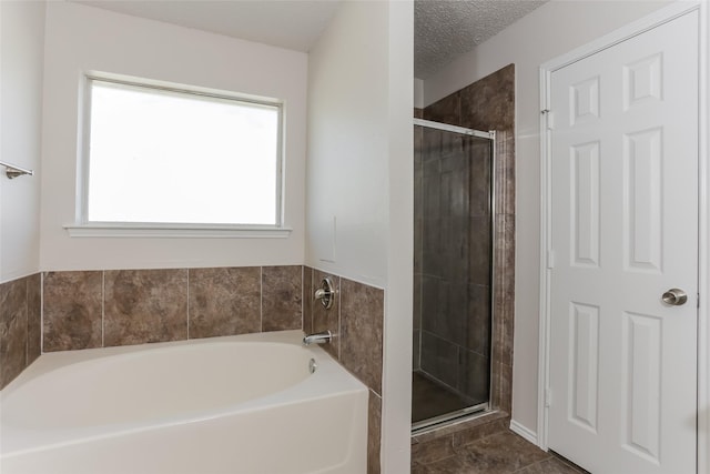 full bath featuring a stall shower, a textured ceiling, and a bath