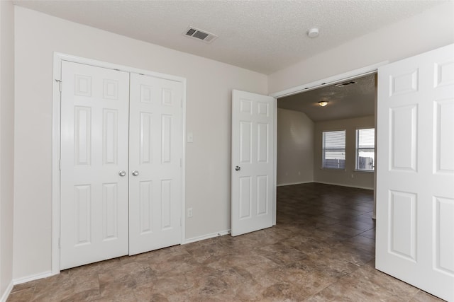 unfurnished bedroom with baseboards, a textured ceiling, visible vents, and a closet