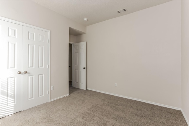 unfurnished bedroom featuring carpet, a closet, visible vents, and baseboards