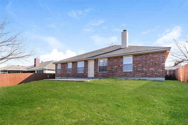 back of property with a lawn, a fenced backyard, a chimney, central air condition unit, and brick siding