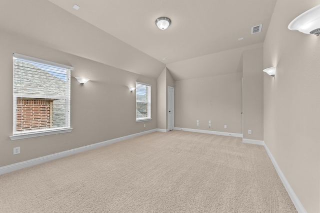 spare room featuring vaulted ceiling, baseboards, visible vents, and light carpet