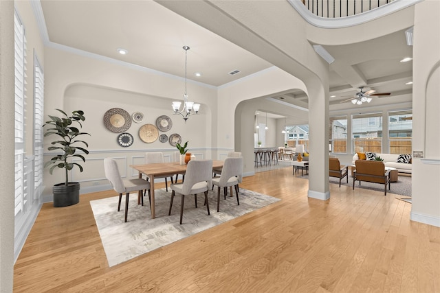 dining room featuring visible vents, ornamental molding, ceiling fan with notable chandelier, light wood-style floors, and arched walkways