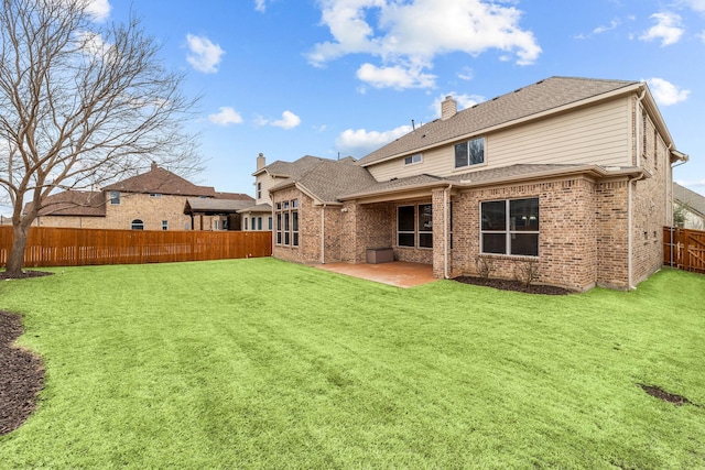 back of house with roof with shingles, a fenced backyard, a chimney, a patio area, and a lawn