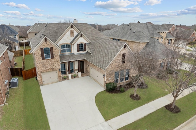 view of front of property with stone siding, roof with shingles, concrete driveway, and a front yard