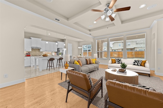 living room featuring visible vents, baseboards, ceiling fan, light wood-style flooring, and coffered ceiling