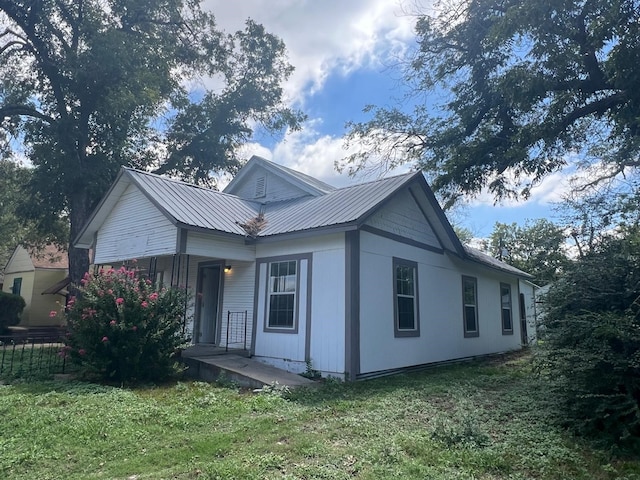 view of front of house with metal roof, a porch, a front yard, and fence