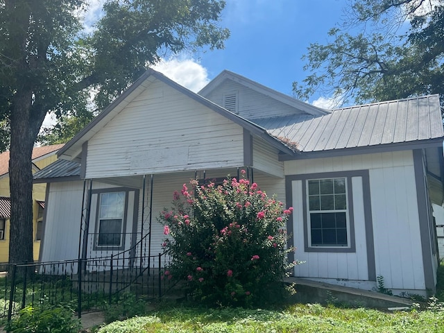 view of side of property with a fenced front yard and metal roof