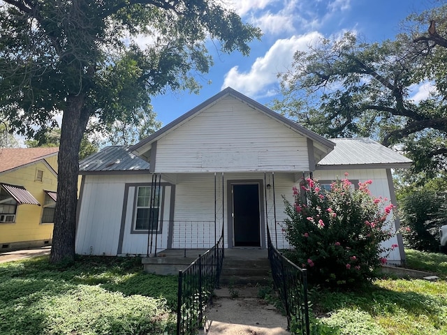 view of front of house with a garage, a porch, and metal roof