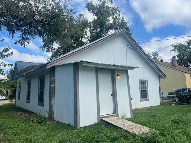 exterior space with metal roof and a yard