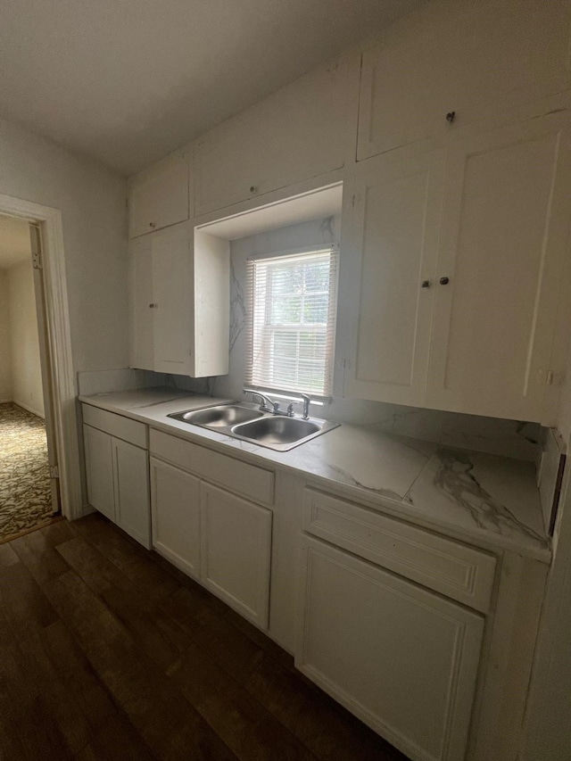 kitchen featuring white cabinetry, dark wood-type flooring, a sink, and light countertops