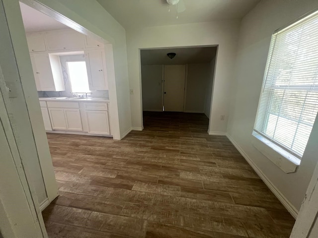 hallway with dark wood-style floors, a sink, and baseboards