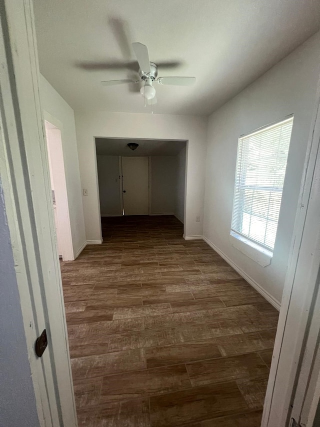 corridor featuring dark wood-style flooring and baseboards