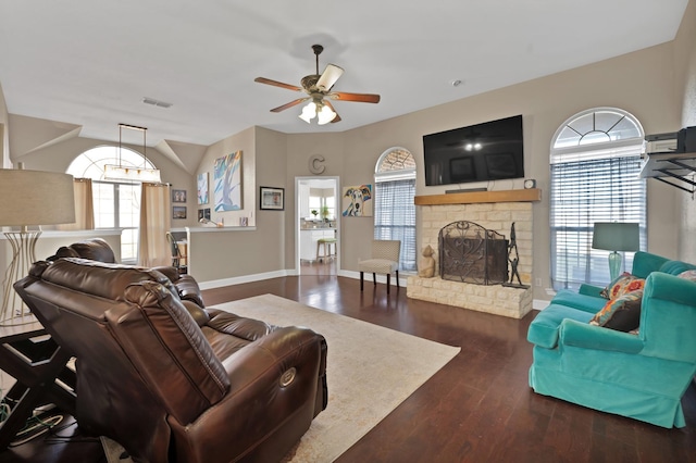 living room with baseboards, visible vents, a fireplace with raised hearth, ceiling fan, and wood finished floors