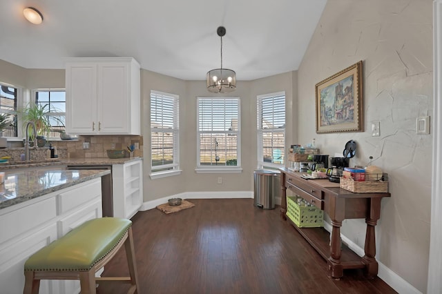 kitchen with light stone countertops, dark wood-style floors, white cabinetry, and a sink