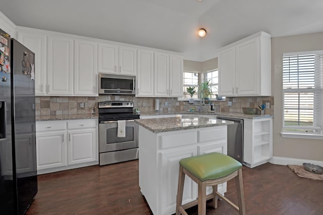 kitchen featuring stainless steel appliances, a kitchen island, white cabinets, dark wood-style floors, and tasteful backsplash