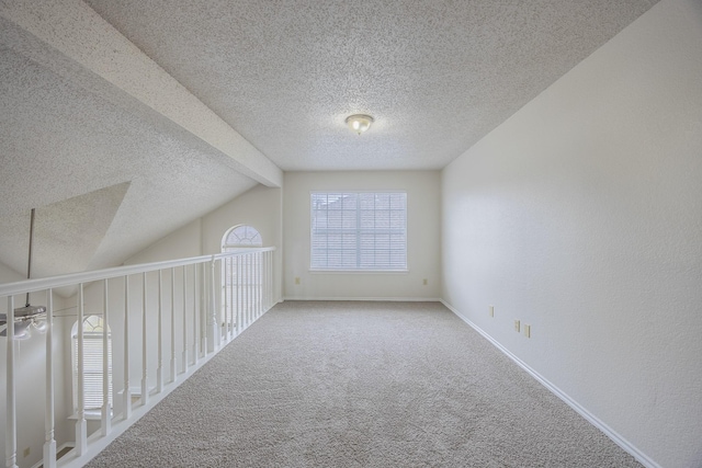 bonus room with carpet flooring, lofted ceiling with beams, baseboards, and a textured ceiling