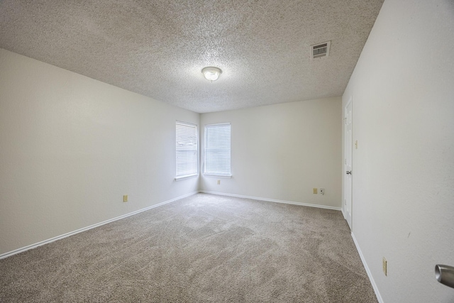 carpeted spare room featuring a textured ceiling, visible vents, and baseboards