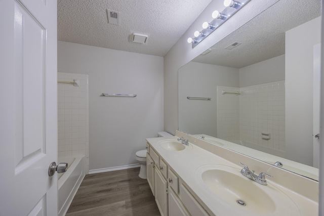 bathroom with double vanity, wood finished floors, a sink, and toilet