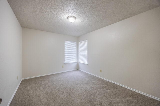 carpeted spare room featuring a textured ceiling and baseboards