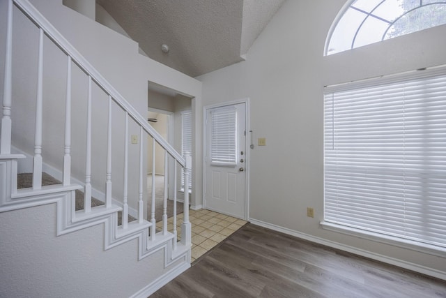 entrance foyer featuring stairs, a textured ceiling, baseboards, and wood finished floors