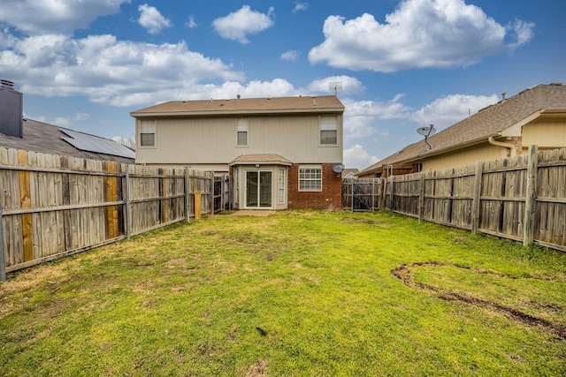 back of house featuring brick siding, a lawn, and a fenced backyard