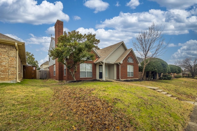 view of front of property featuring a front yard, a chimney, fence, and brick siding