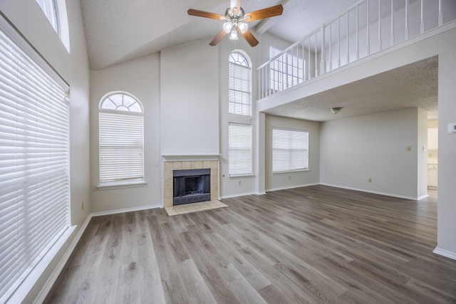 unfurnished living room featuring a towering ceiling, baseboards, and wood finished floors