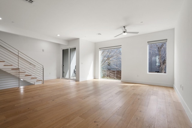 unfurnished living room featuring light wood-style floors, plenty of natural light, stairway, and baseboards